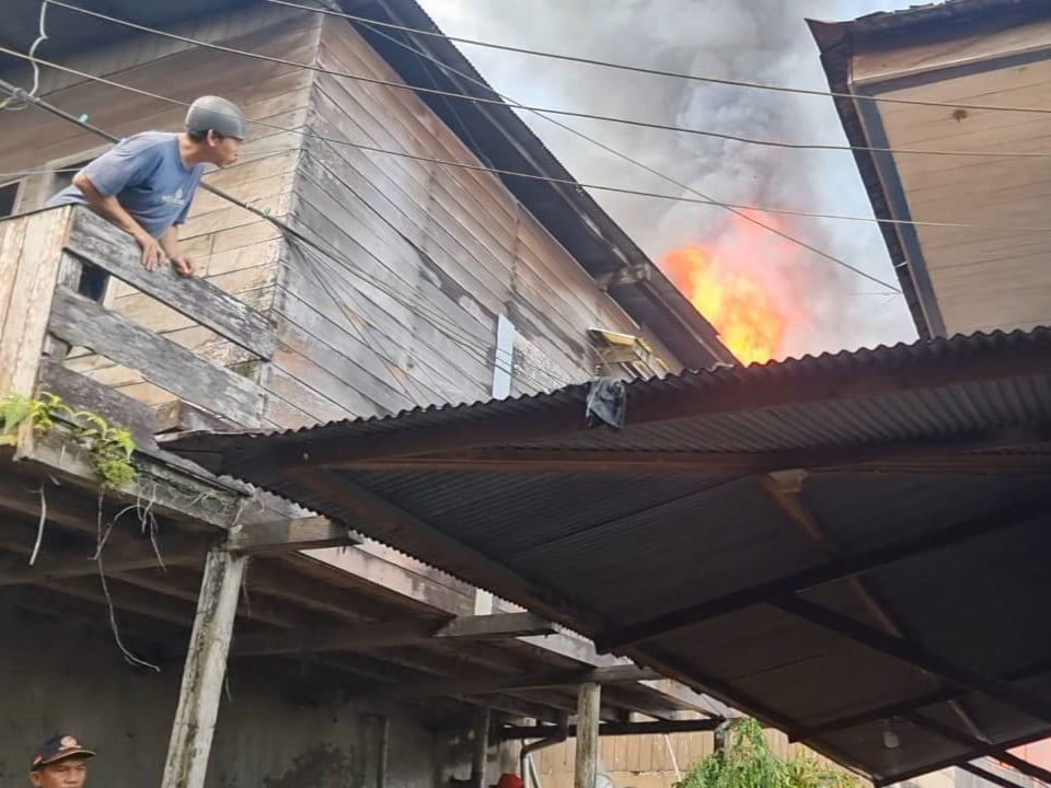 Seorang pria sedang memastikan rumahnya yang sangat dekat dengan amukan si jago merah di gang Sederhana, Jalan RE Martadinata, Teluk Lerong Ilir, Kota Samarinda. (Foto/HI)